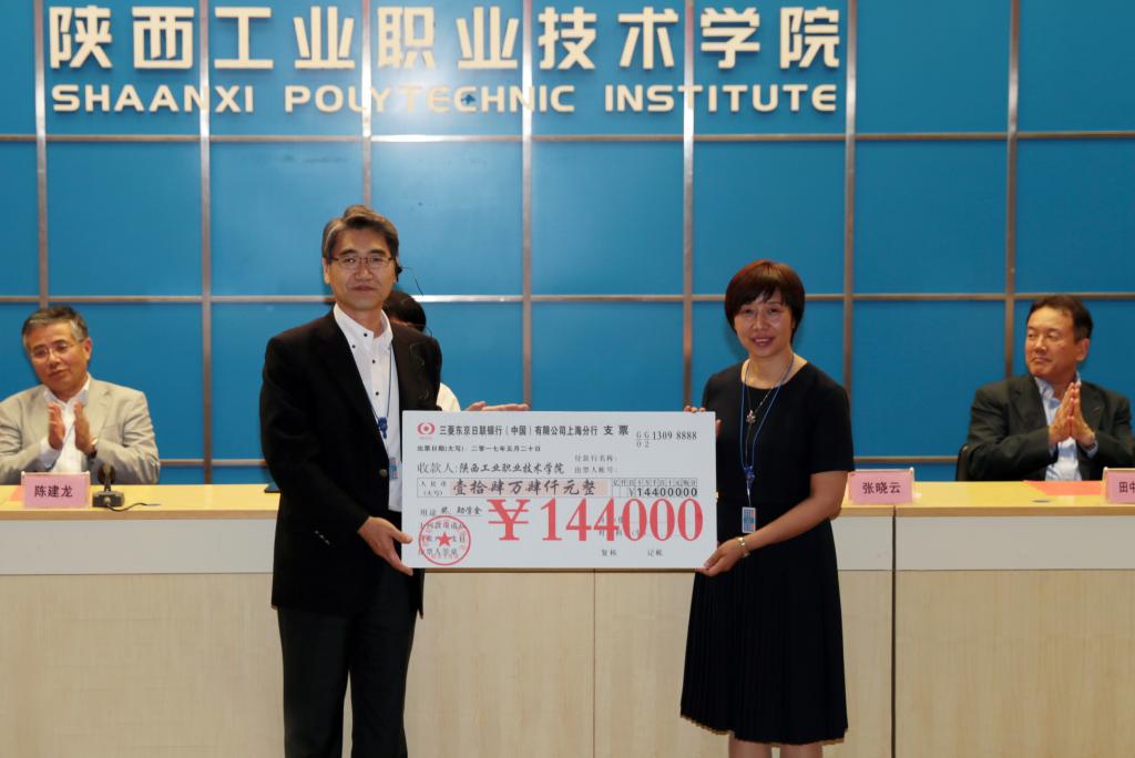 张晓云院长从中道教顕总经理手中接过欧姆龙捐赠的14.4万元的奖学金